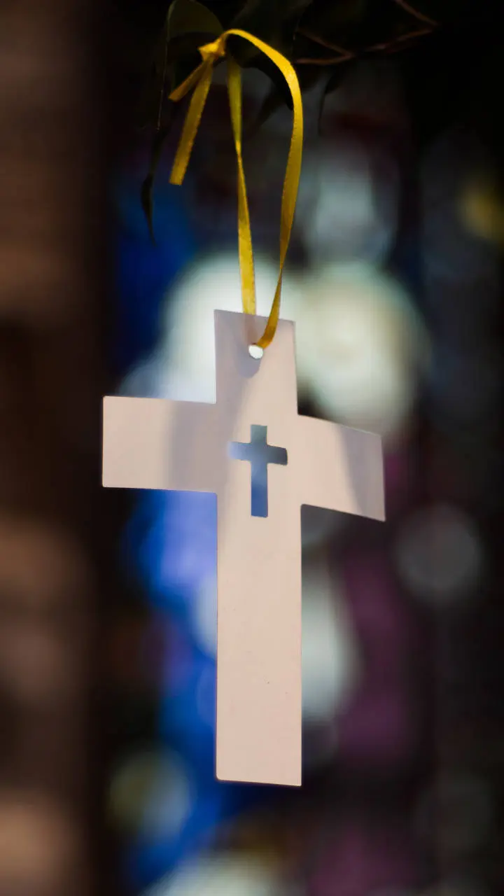 A handmade paper cross in front of a stained glass window